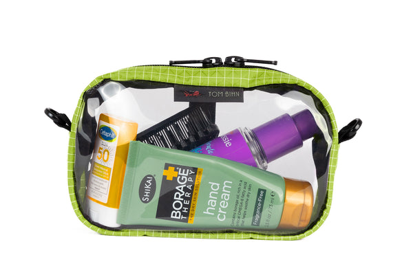 A Kiwi (bright green with white grid pattern) Halcyon 3D Clear Organizer Cube filled with sundries.